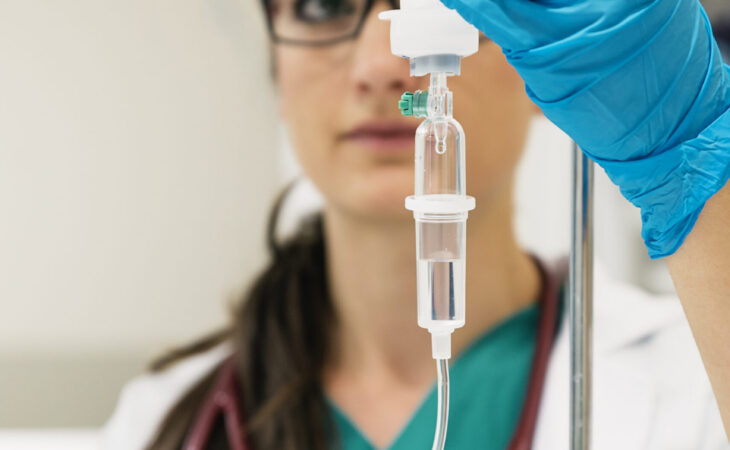 Young woman doctor anesthesiologist dressed in green gown, puts the dropper in hospital room